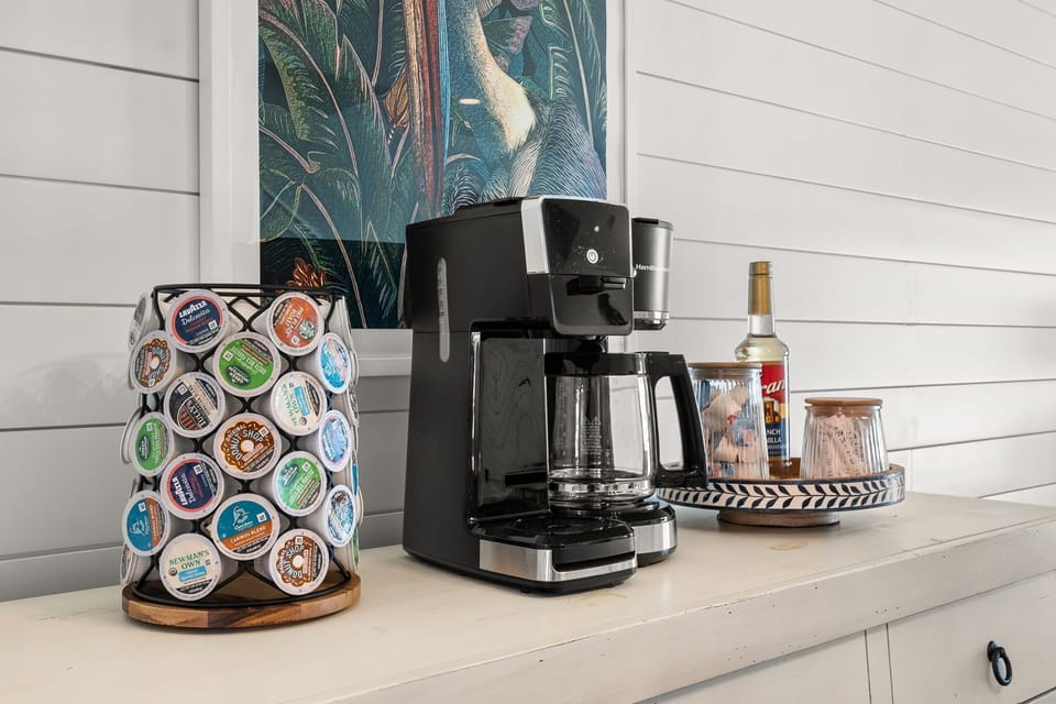 The fully stocked coffee bar features a selection of kcups, creamer, sugar, and syrup. The coffee marker is drip, kcup and even makes cold brew!