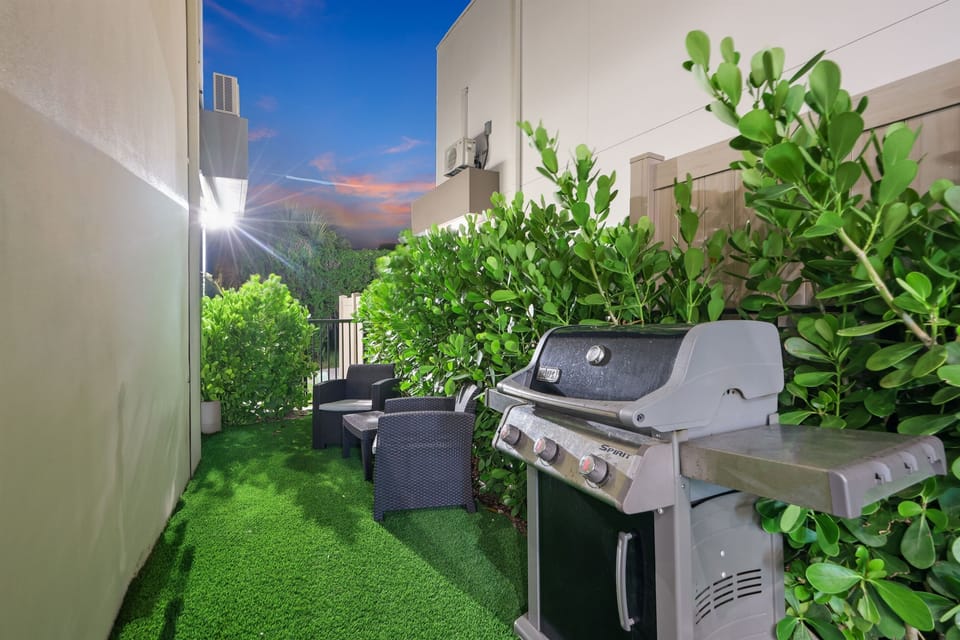 Enjoy your own outdoor patio with a BBQ grill, seating, and tropical greenery—perfect for a relaxed evening after exploring Delray.