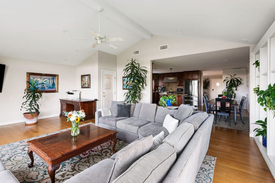 Relax in a bright, open living room featuring a plush sofa, ample seating, and beautiful garden views through sun-filled windows