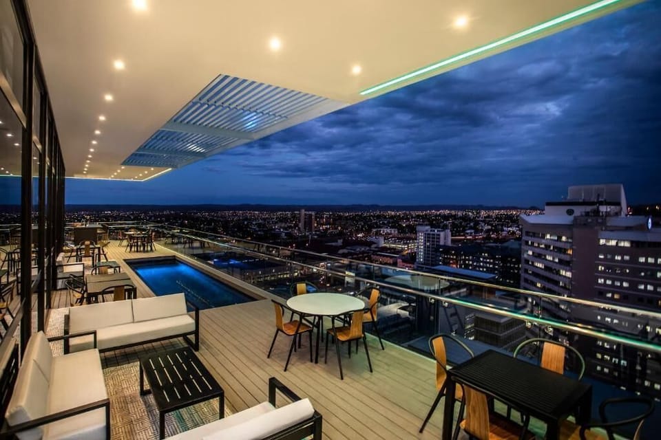 Unwind poolside as city lights sparkle across the skyline.