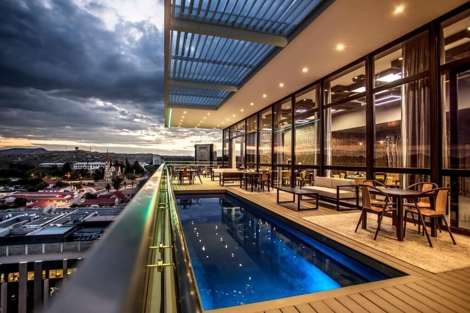 Sip and swim above the city under glowing evening lights.
