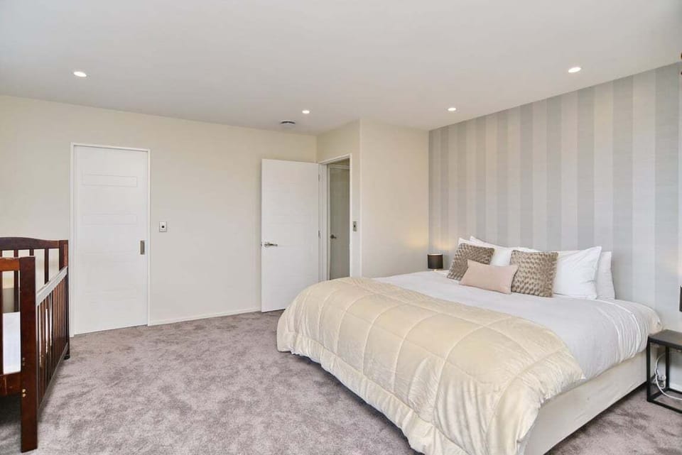 Bedroom 2 (Upstairs) – Features a super king bed, ensuite with bath and shower overhead, and includes a desk and cot — ideal for parents or guests travelling with a baby.