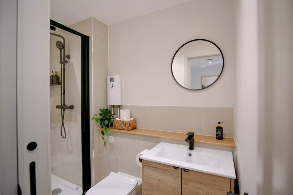 Shower, round mirror, bathroom essentials, and sink