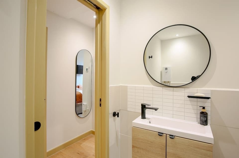 Bathroom doorway, round mirror, and sink