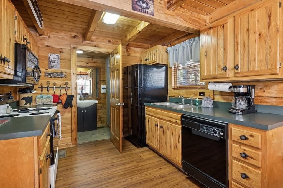 Warm wood tones and classic black appliances create a cozy, cabin-style kitchen.