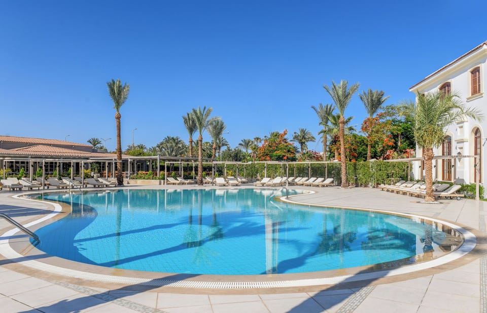 Admire sunlit resort architecture beside tranquil, curved pool edges.