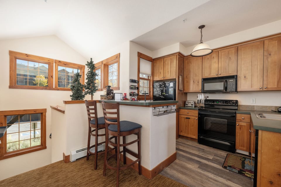 Cook your favorite meals at Kicking Horse Palomino 7-302 in this fully-equipped kitchen with warm wood cabinets, modern appliances, and a cozy breakfast bar for morning coffee.