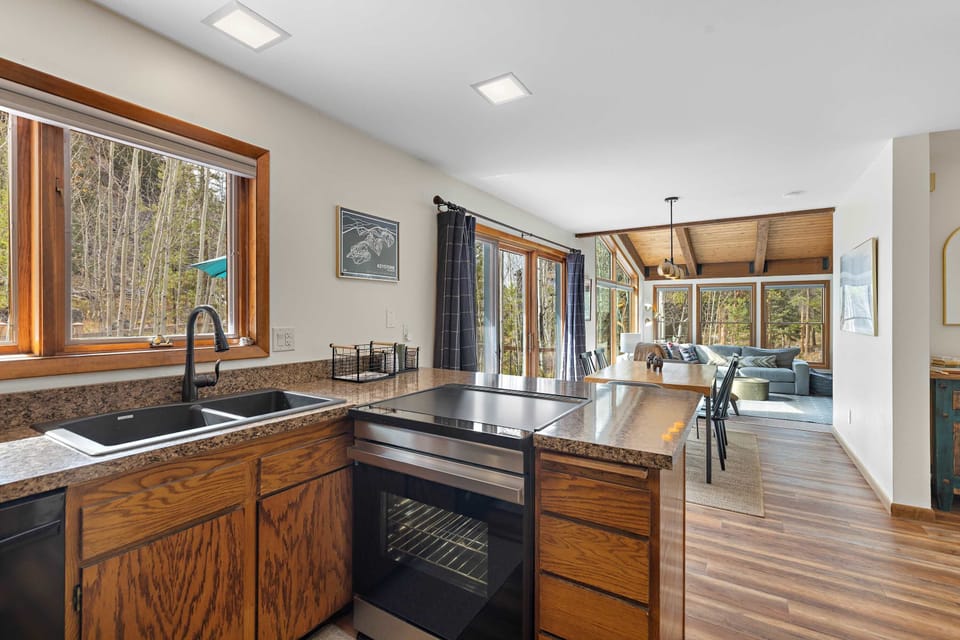 Fully-equipped kitchen with stainless steel fridge and forest views.