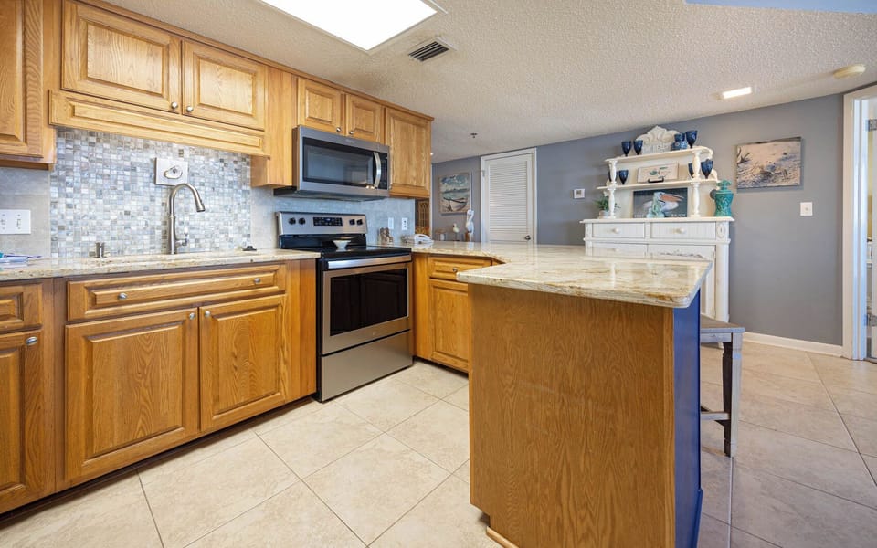 Warm wood cabinetry complements the granite countertops in this kitchen, featuring a breakfast bar and decorative accents