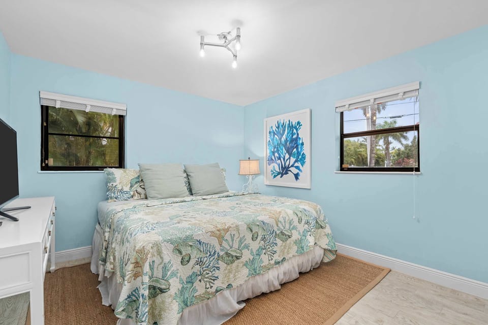 King bedroom with soft coastal tones and peaceful views from both windows.