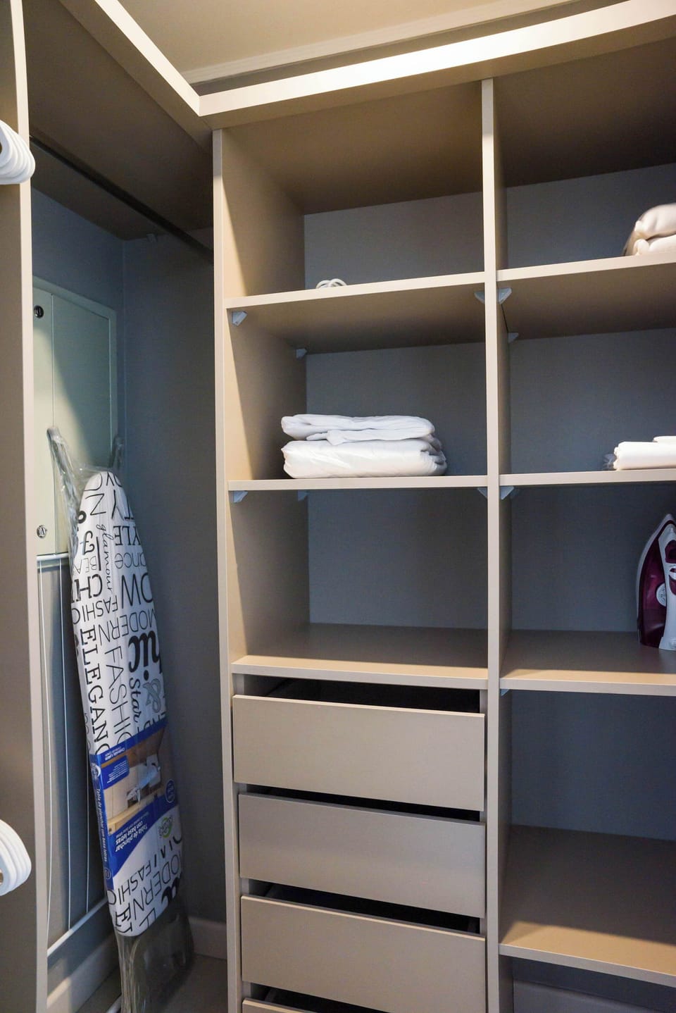 Spacious closet with ample storage, linens, and ironing essentials for a comfortable stay.