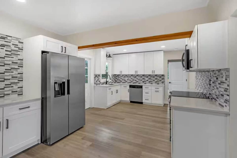 Cook and snack with ease in this modern kitchen, featuring clean white cabinetry, plenty of counter space, and a stainless-steel fridge for stocking up.