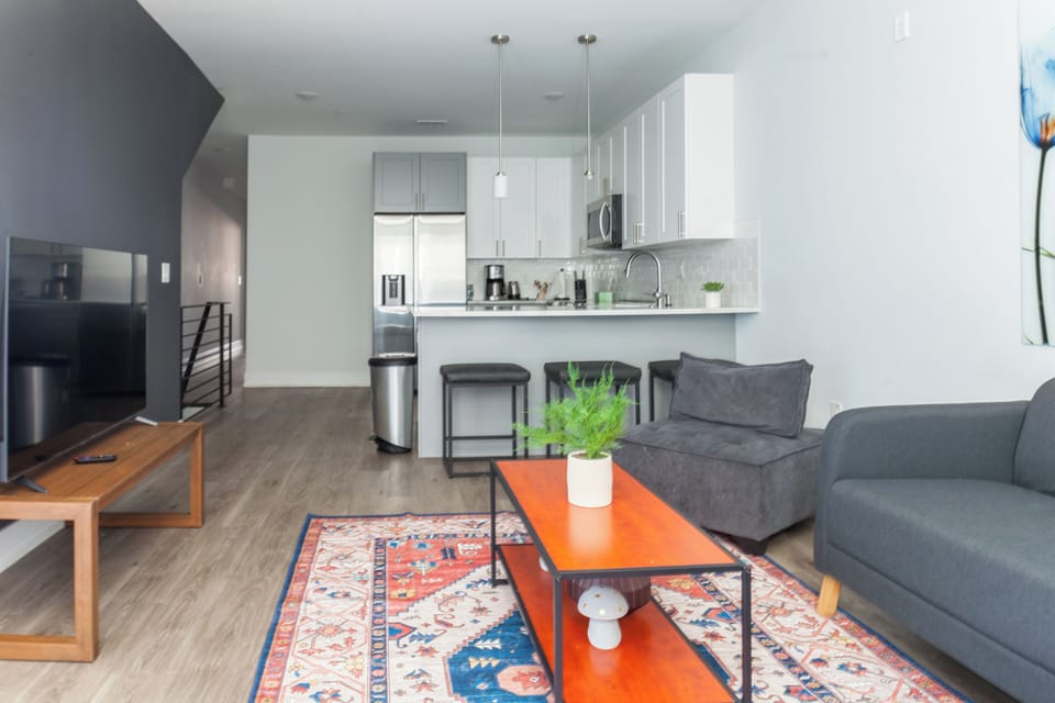 Step into our inviting living room, where a plush sectional couch beckons for relaxation after a day of exploration. The entertainment center boasts a state-of-the-art smart TV for your viewing pleasure #WelcomingSpace #ColorfulVibes