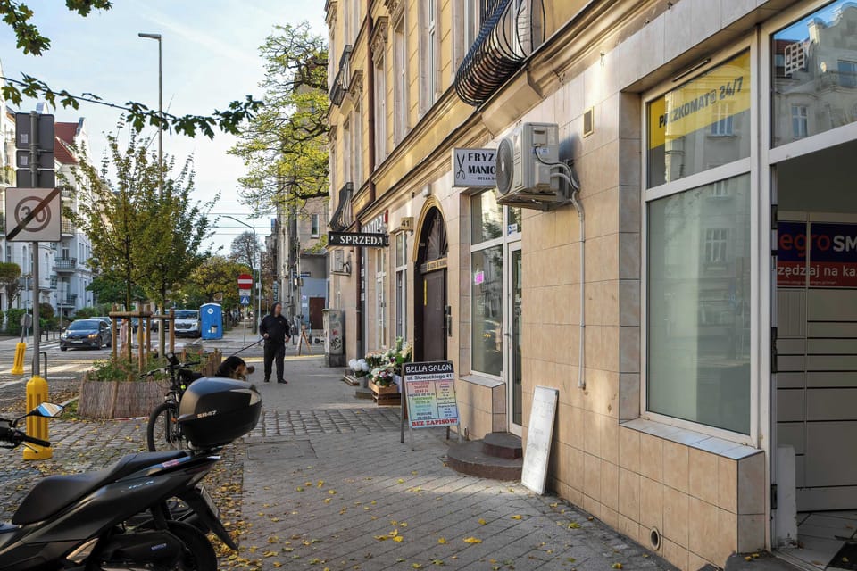The entrance to the townhouse surrounded by small shops and cafés highlights the local character and everyday convenience of the area.