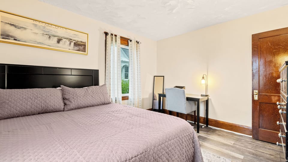 King bedroom with original woodwork and a writing desk by the window