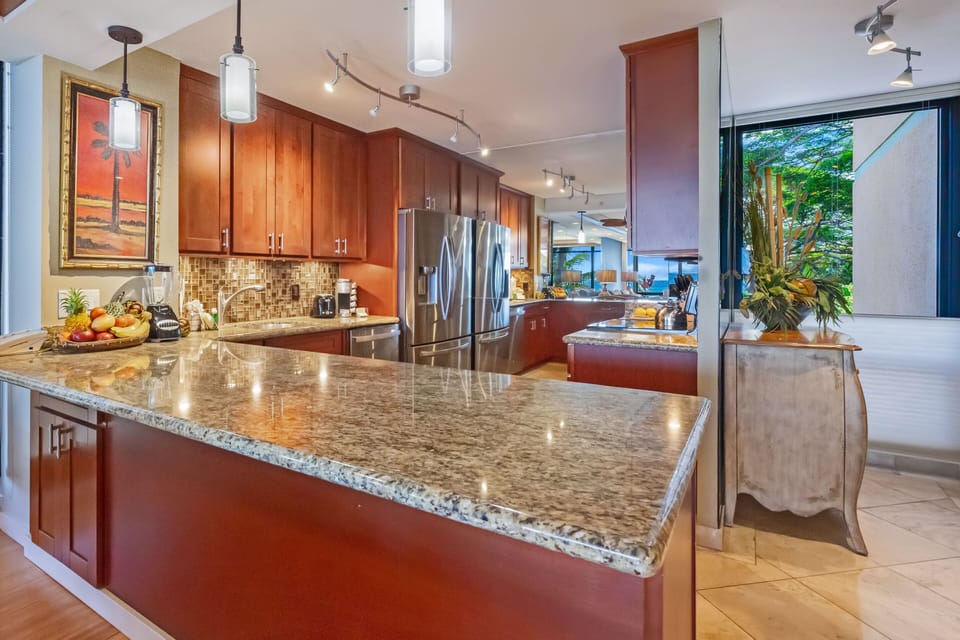 Spacious kitchen with a large granite island, stainless steel appliances, and rich wood cabinetry.