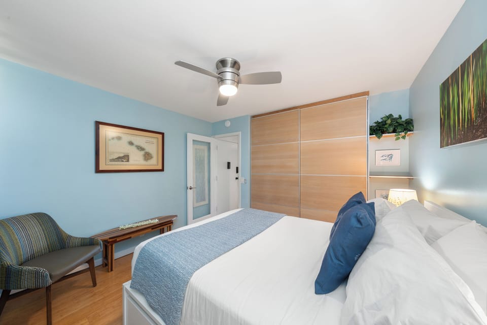 Spacious bedroom with modern sliding closet doors, hardwood flooring, and clean coastal design.