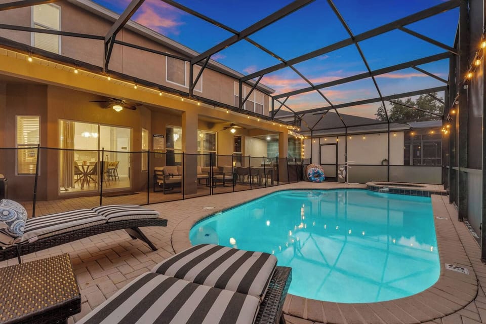 Screened Pool: The pool is framed by the covered patio and dining area, all lit up as the sun sets!