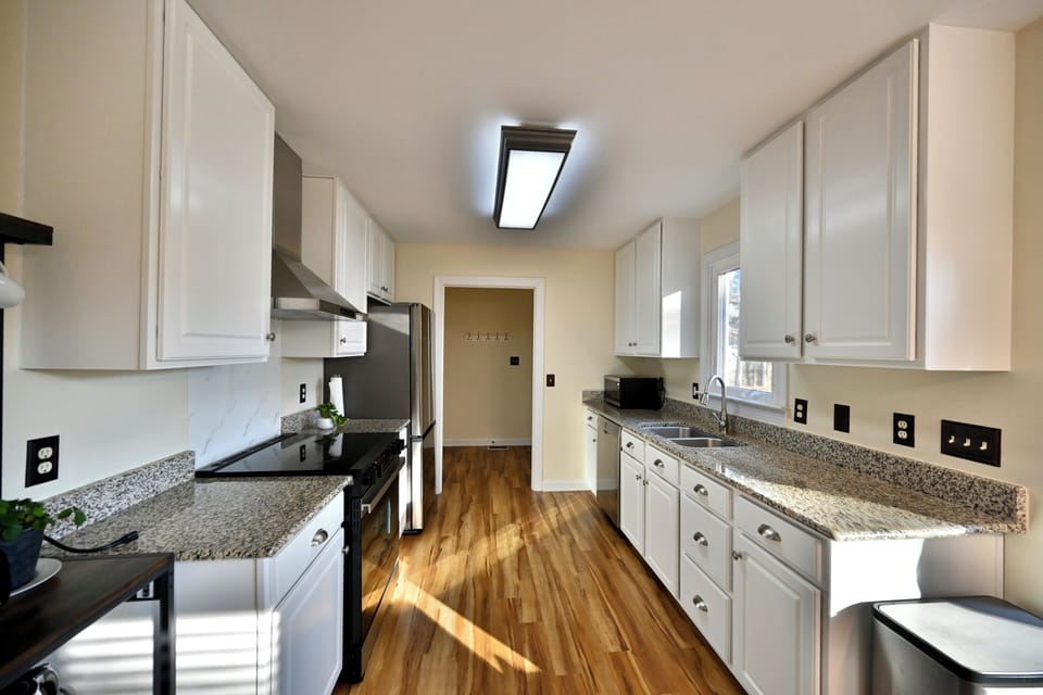 Bright galley kitchen with granite counters and full appliances