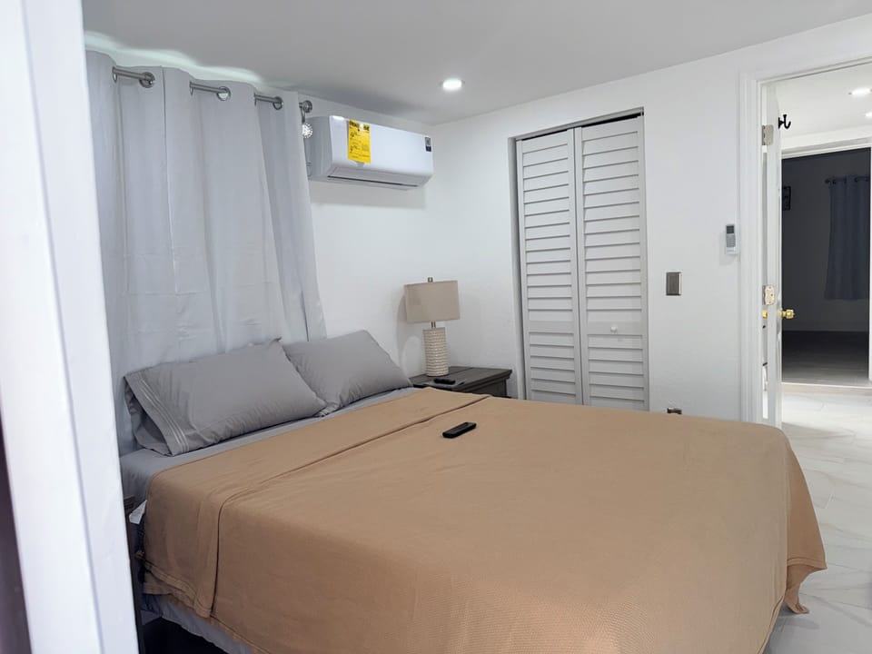 Step into your serene bedroom retreat where crisp white walls and soft gray linens create the perfect atmosphere for restful nights. Cool air conditioning keeps you comfortable while modern amenities surround you.