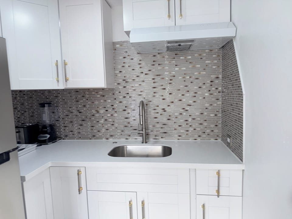 Your private kitchen features gleaming white cabinets and elegant mosaic backsplash that catches the light beautifully. You'll love preparing meals with modern appliances and plenty of counter space.