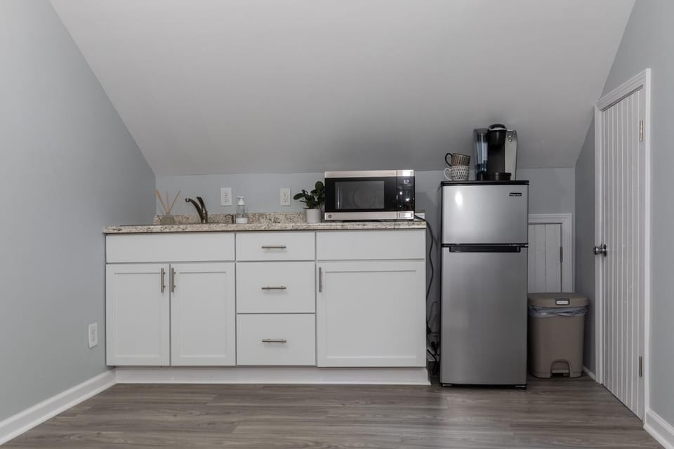 Modern kitchenette with white cabinets, stainless steel appliances, and sink.