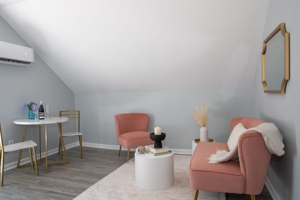 Stylish attic living space with pink seating and a small dining area.