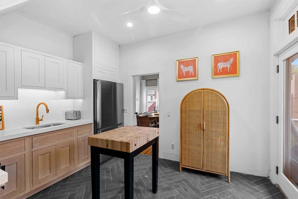 The kitchen features a butcher block island, herringbone floors, and direct sightlines to the dining area.