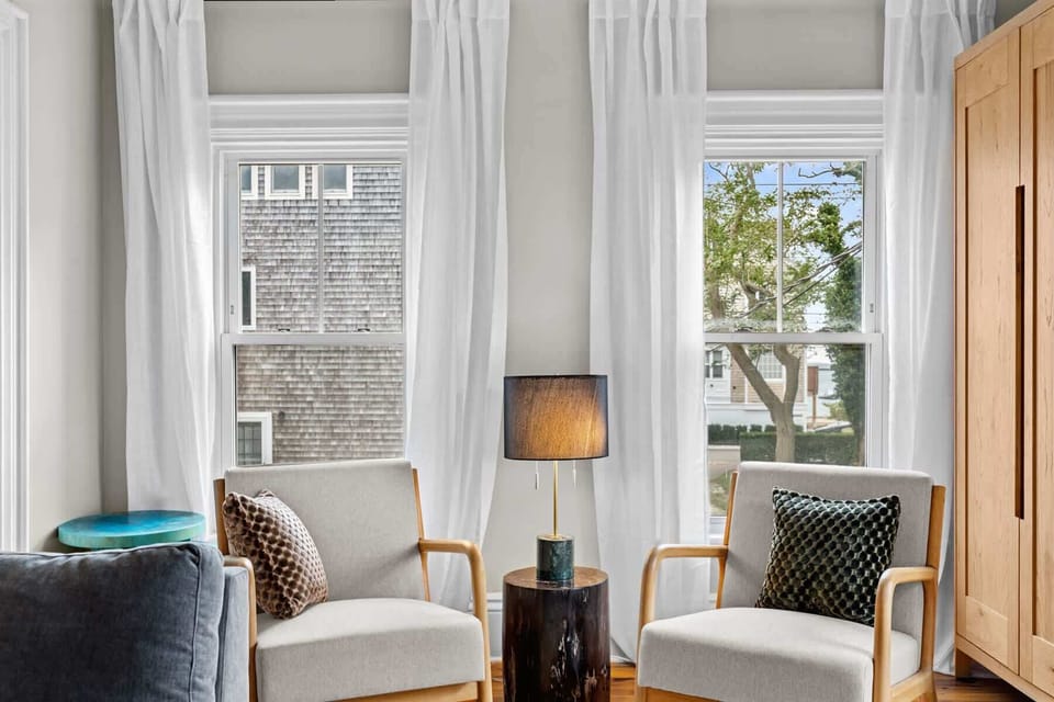 Sunlight streams through large windows framing cozy accent chairs, perfect for morning coffee or evening conversation.