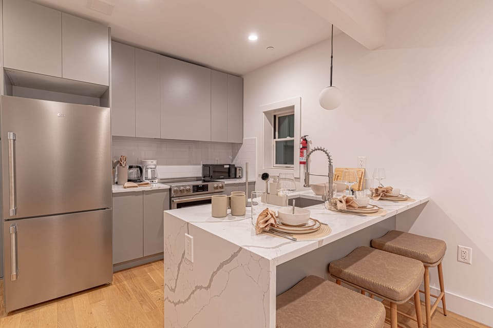 Modern open kitchen with stainless appliances, island seating and cookware for home-cooked meals.