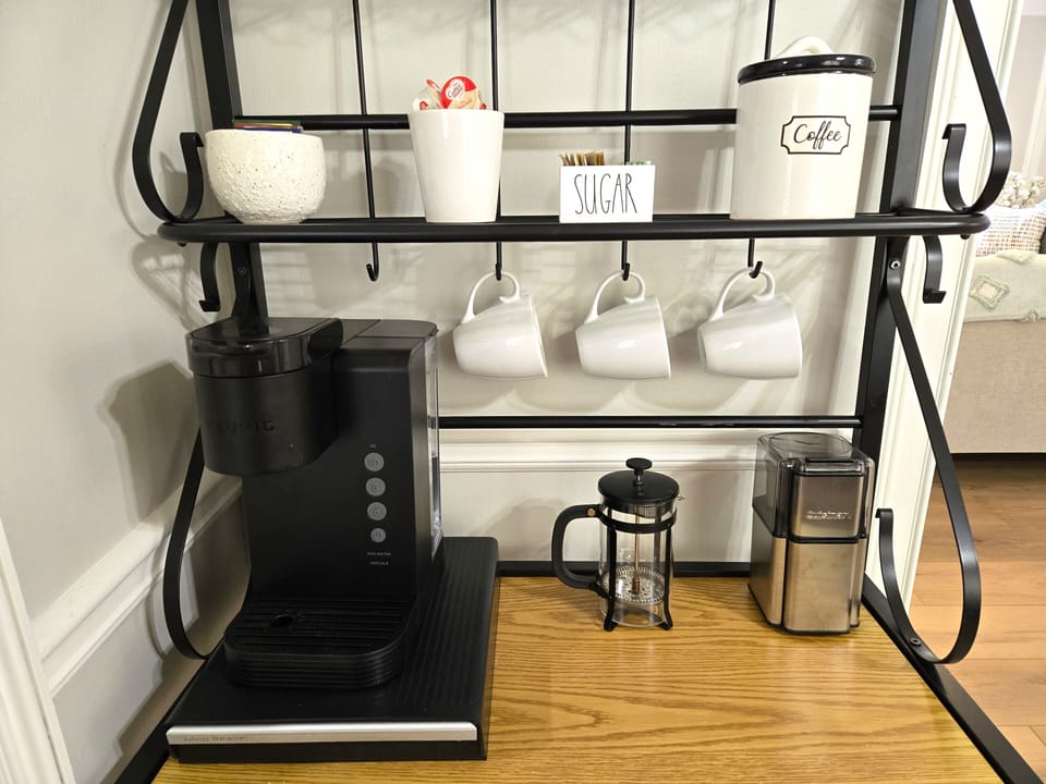 Coffee station equipped with a keurig (coffee pods in the drawer underneath), french press, and coffee bean grinder