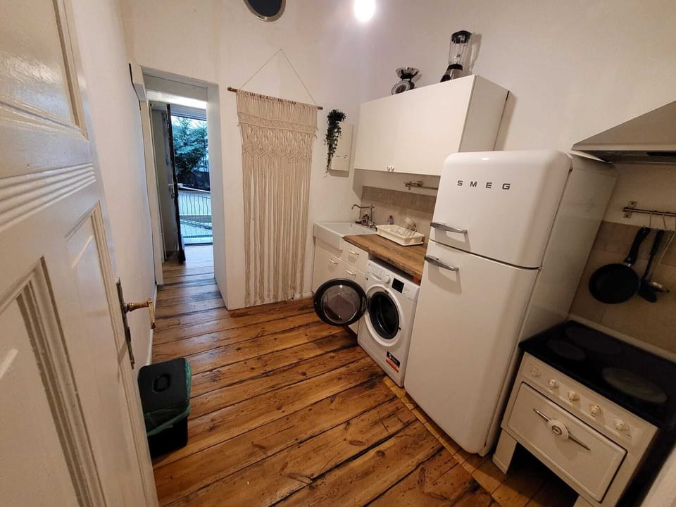 Charming kitchen with SMEG fridge, washer, and warm wooden floors.