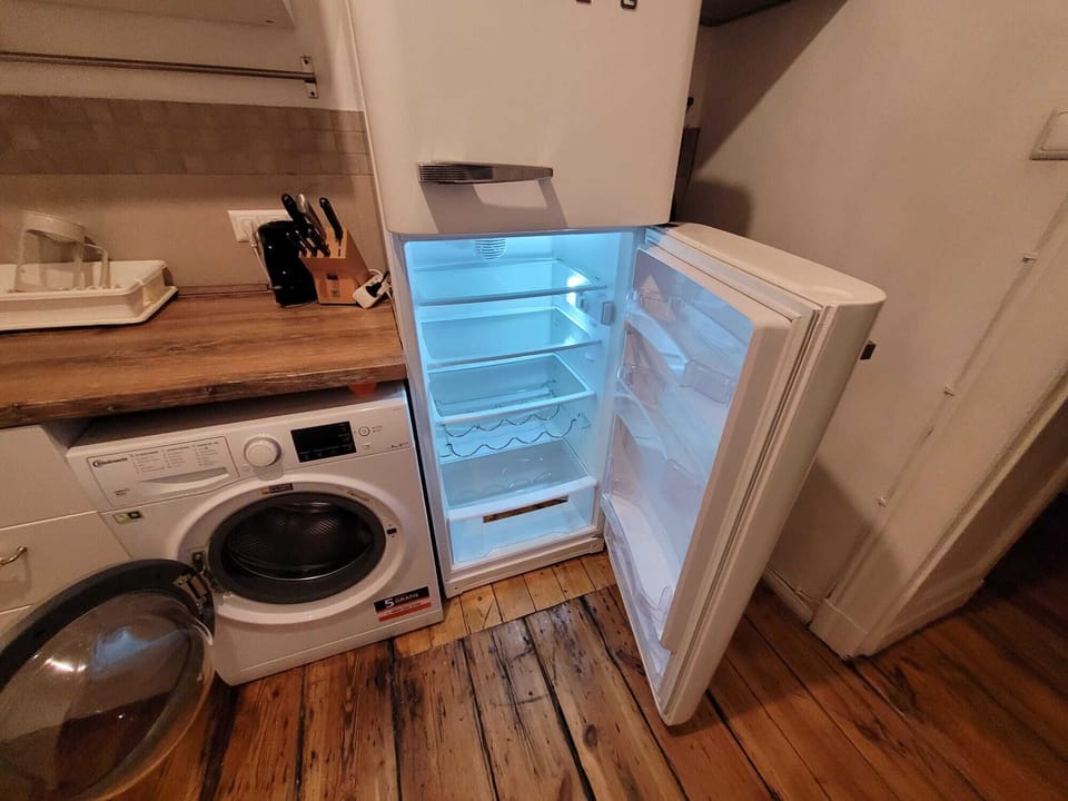 Compact kitchen with fridge, washer, wooden countertop, and essential appliances