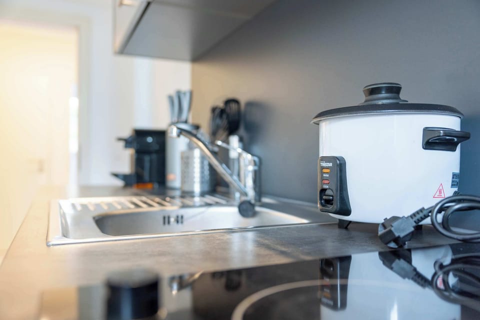 Modern kitchen setup with stovetop, kettle, and rice cooker
