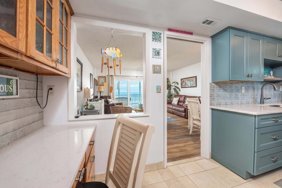 Cozy kitchen with blue cabinetry and ocean views from the living area.