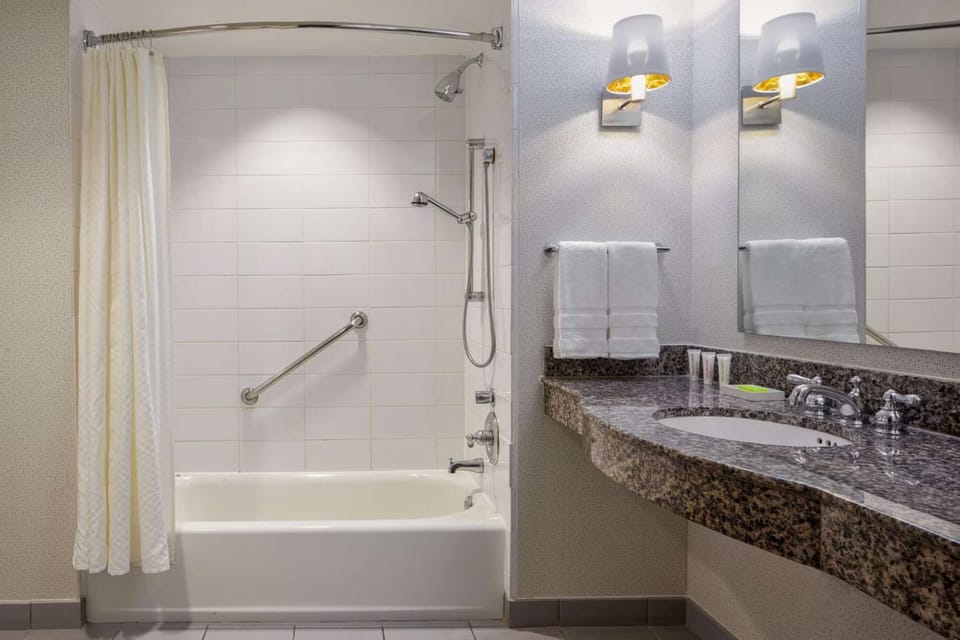Clean bathroom with tub, grab bars, and large granite sink