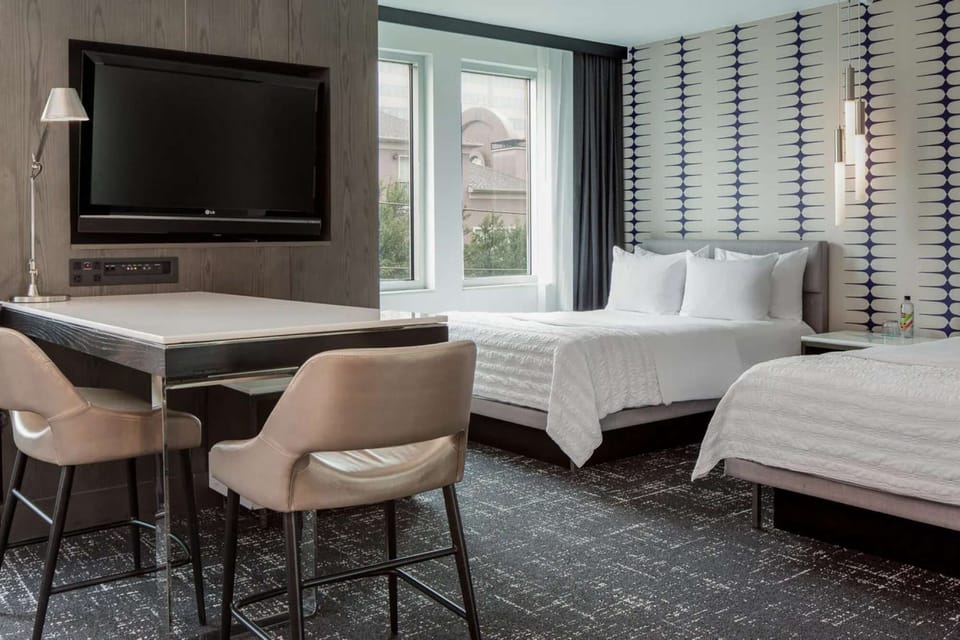 Bright room with two beds, work desk, TV, and tall windows