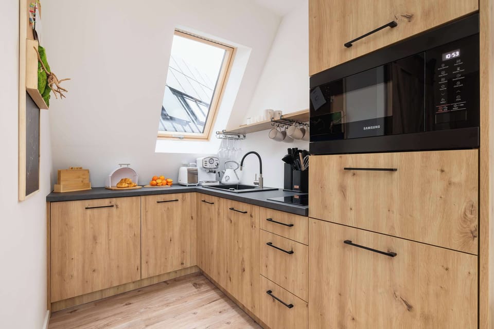 A view of the kitchen corner showing built-in appliances and a clean countertop. The wooden cabinetry gives it a cozy, cabin-like feel.