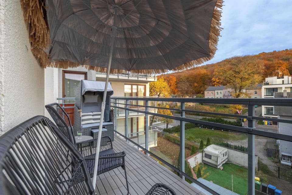 A balcony with outdoor chairs and a straw umbrella offering shade and comfort.