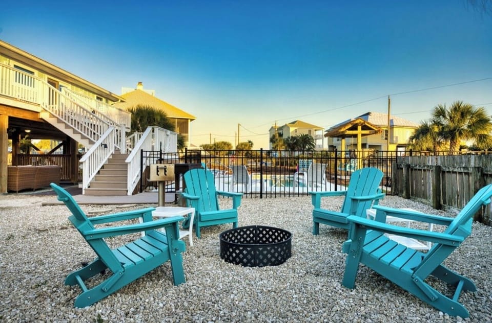 Gather around the fire pit in turquoise Adirondack chairs as the day winds down, with your coastal retreat just steps away.