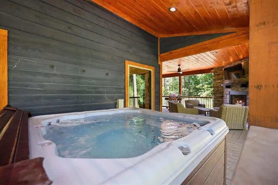 Private hot tub on covered deck with fireplace and peaceful forest views