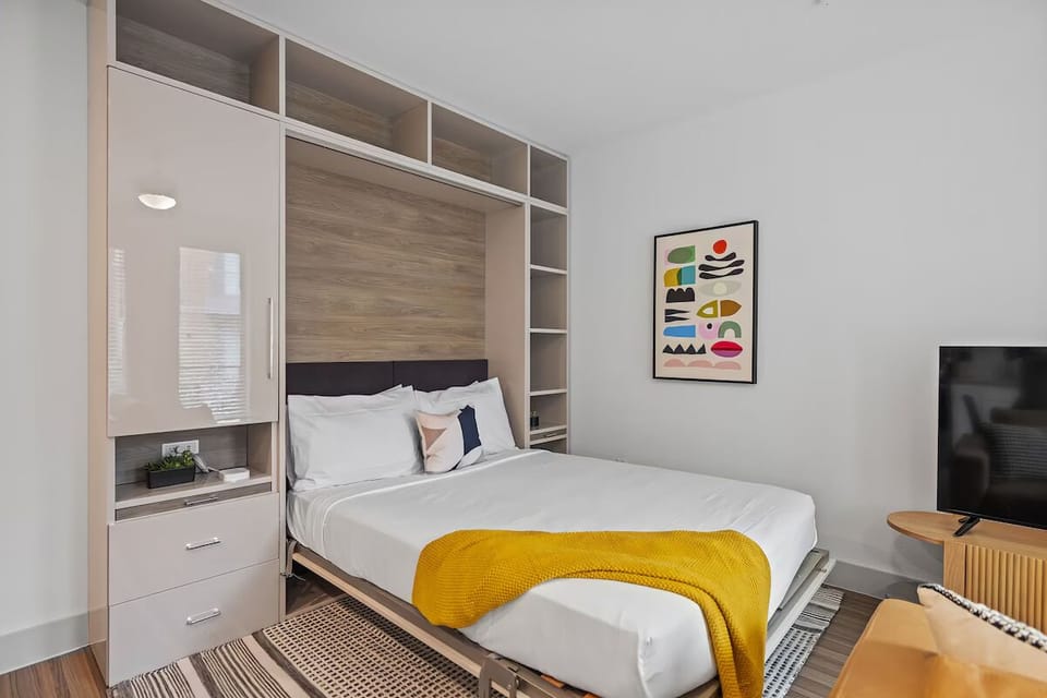 Unwind into crisp linens beneath sleek built-in storage.