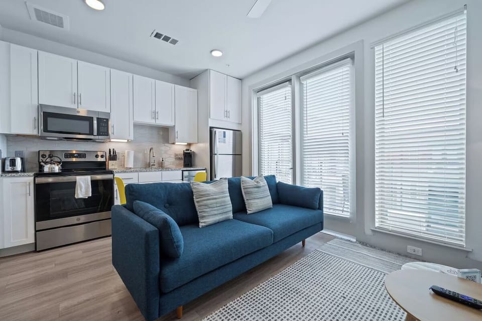 Relax on the plush sofa beside sunlit, floor-to-ceiling windows.