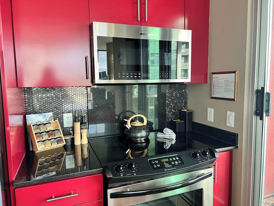 Contemporary kitchen with red cabinetry, black granite countertops, and stainless steel appliances. Features a sleek backsplash, modern finishes, and thoughtful touches—perfect for cooking and entertaining in style.