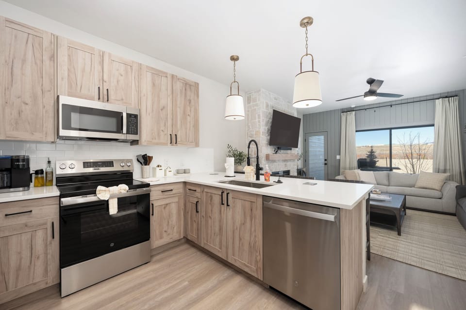Your modern kitchen awaits with stainless steel appliances, warm wood cabinets, and quartz countertops perfect for preparing memorable meals.