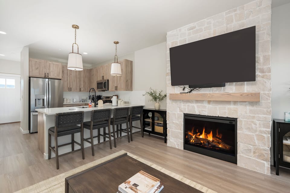 Your open-concept living space combines a fully equipped kitchen with a cozy fireplace, perfect for cooking and unwinding after mountain adventures.