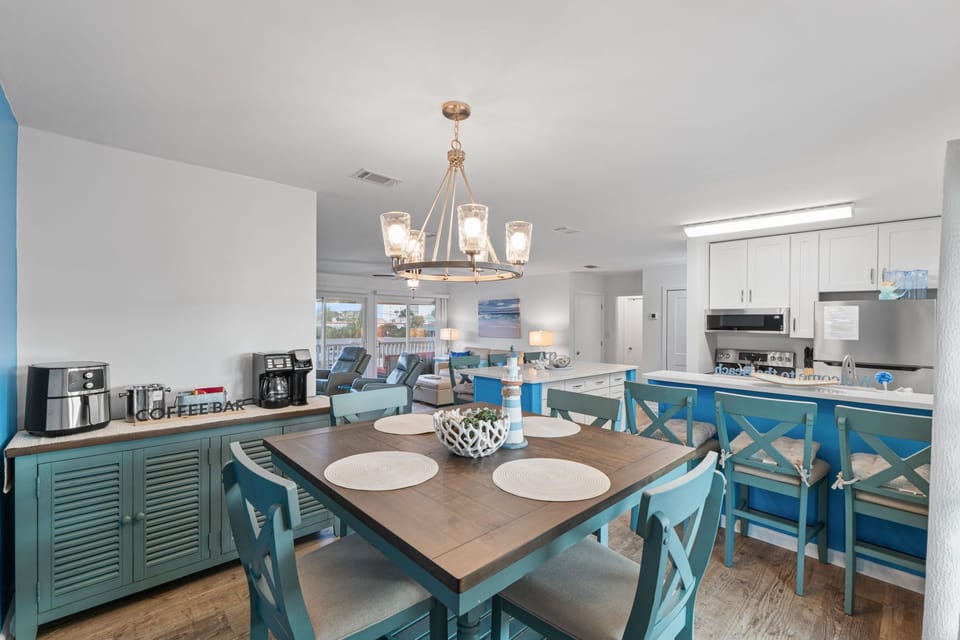 Gather around the coastal-inspired dining table where turquoise chairs create the perfect spot for your morning coffee and vacation planning.