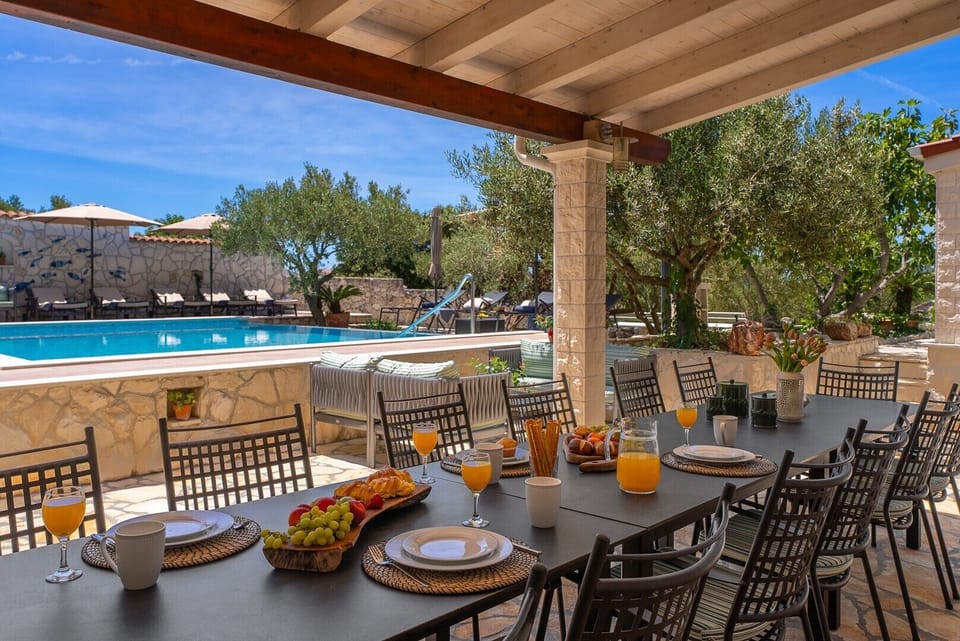 The covered outdoor dining area accommodates up to 14 guests for al fresco meals, perfectly positioned at pool level.