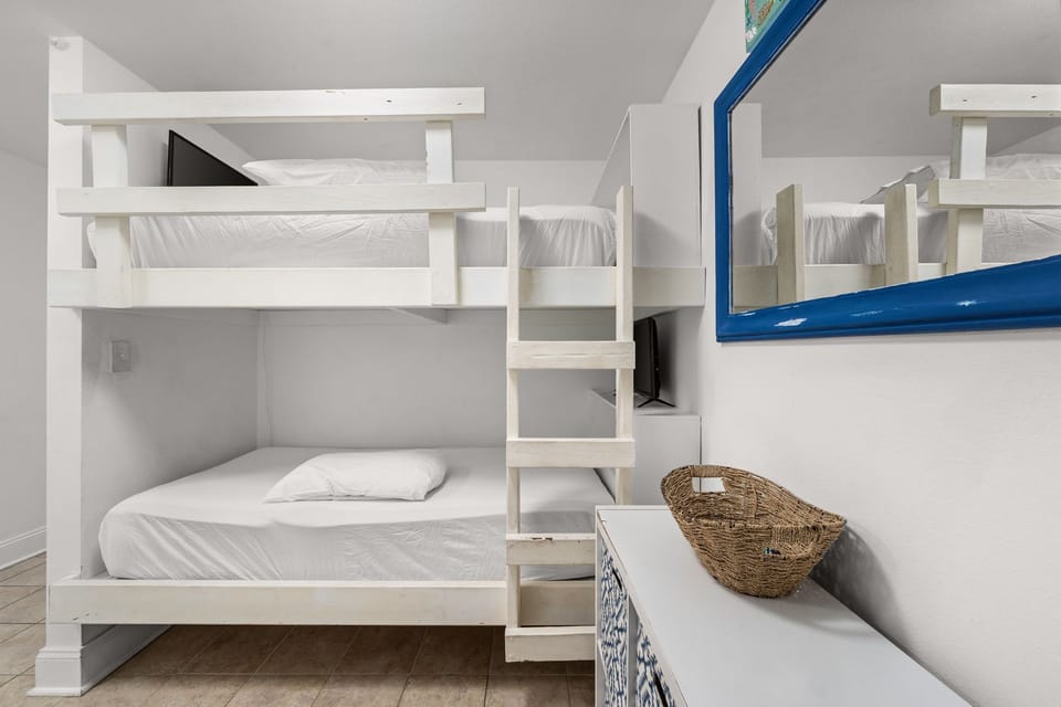 Compact bunk bed setup with clean white linens and a simple ladder for easy access.