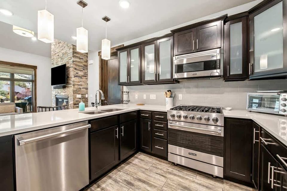 Kitchen equipped with Viking appliances and stocked with crockery (plates, cups, bowls), flatware (forks, spoons, knives), and cookware